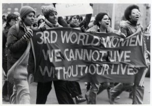 Black women marching with a banner reading "3RD WORLD WOMEN WE CANNOT LIVE WITHOUT OUR LIVES"