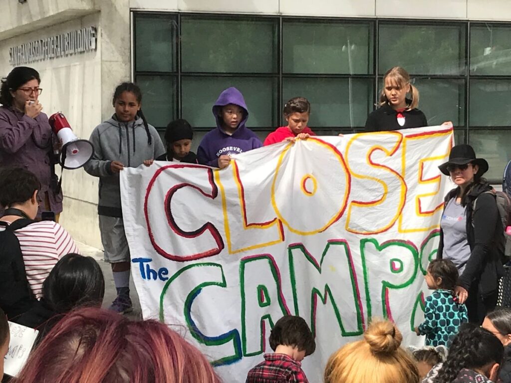 Young protesters hold a banner that reads "Close the Camps" at a Play Date Protest in San Francisco, CA